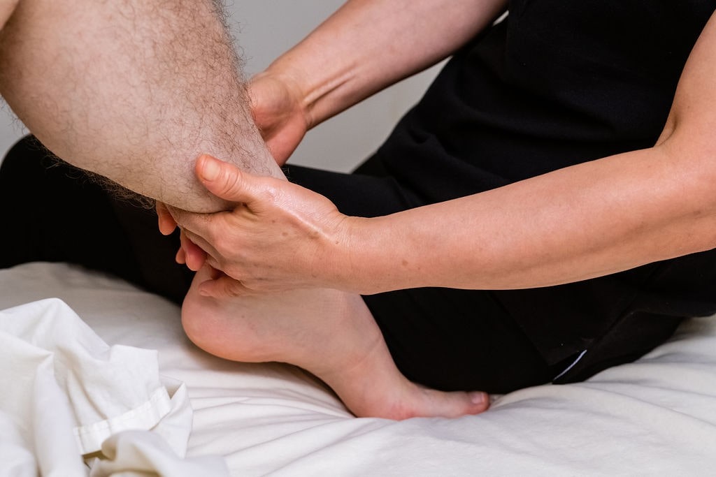 Chinese therapist massaging deep the lower leg
